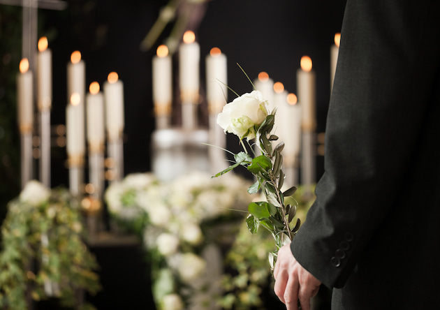Man holding white rose in front of candles