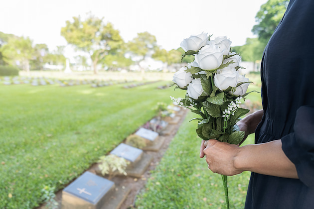 Women holds white roses over cremation headstones