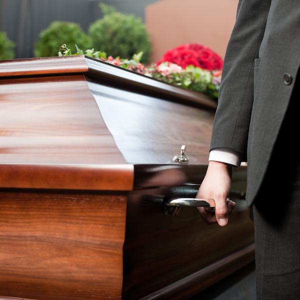 Man in black suit carrying casket