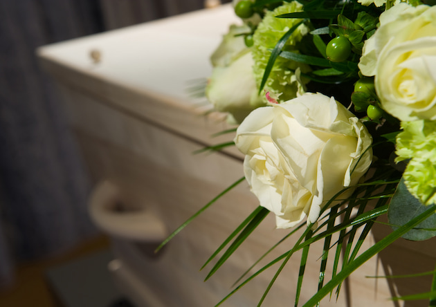 White rose on top of light wooden coffin