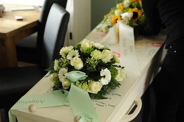 White rose and daisy wreath on top of white coffin